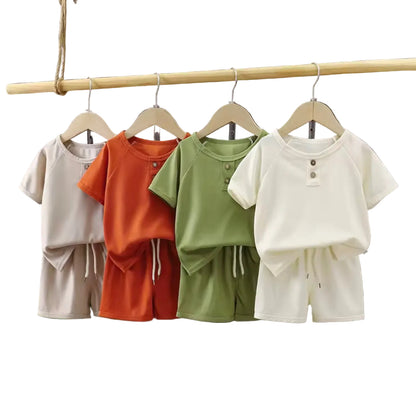 Four children's outfits on hangers against a dark curtain background