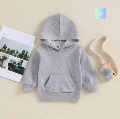Gray hoodie on a beige background with a magazine and toy.