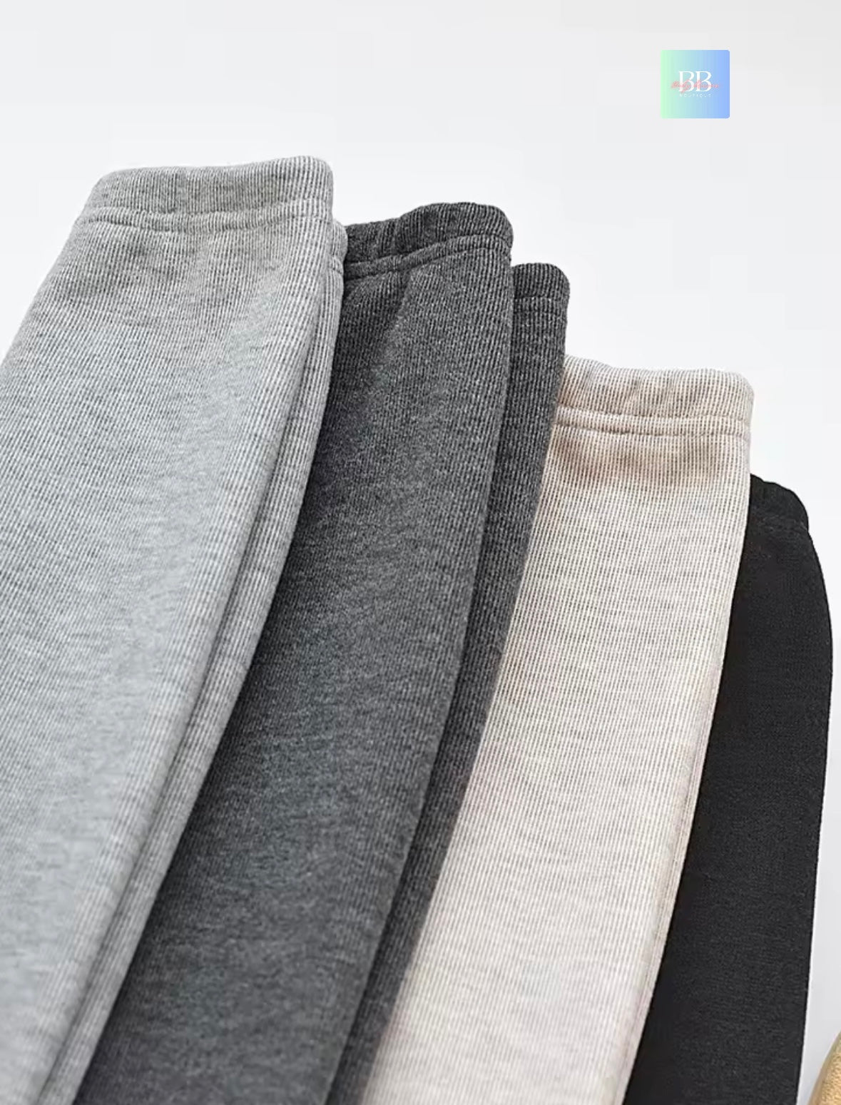 Four pairs of gray sweatpants stacked on a white background