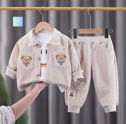 Children's corduroy outfit with teddy bear designs on a hanger against a gray curtain background.