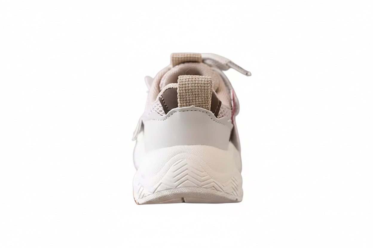 White sneaker with brown accents held by a hand against a blurred background