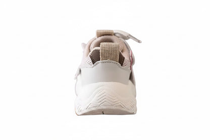 White sneaker with brown accents held by a hand against a blurred background
