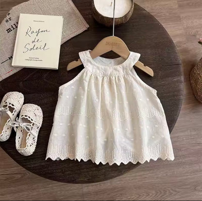 White lace dress on a wooden hanger with white shoes and a book on a wooden surface