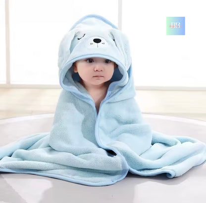 Child wrapped in a blue hooded towel with bear design on a light background