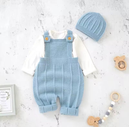 Light blue knitted romper with matching hat on a white surface with toys around