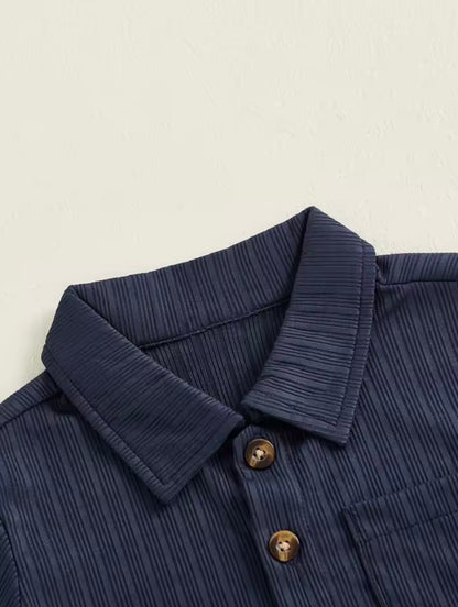 Close-up of a navy blue textured shirt collar with buttons on a beige background