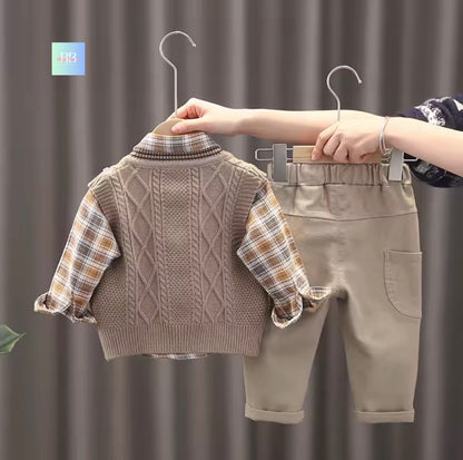 Children's clothing set with sweater and pants on hangers against a neutral background