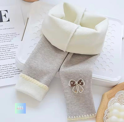 Gray baby pants with white cuffs and a butterfly patch on a white surface.