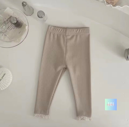 Beige leggings with lace trim on a white surface