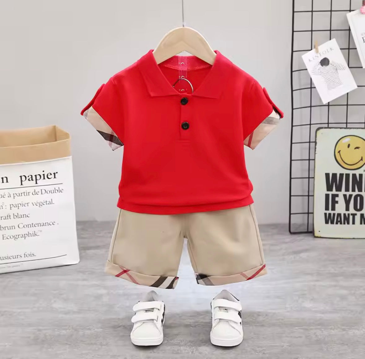 Red polo shirt and beige shorts set on a hanger against a neutral background