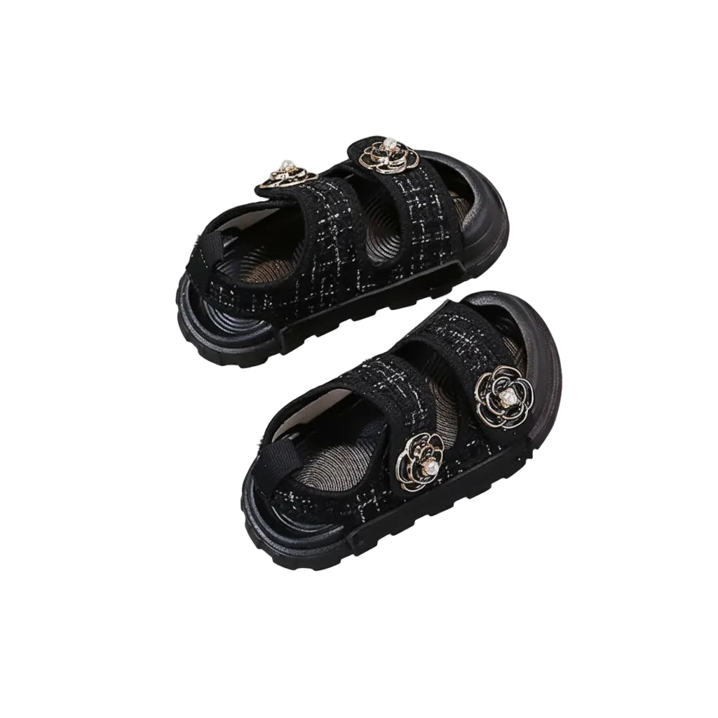Black sandals with decorative elements on a gray surface