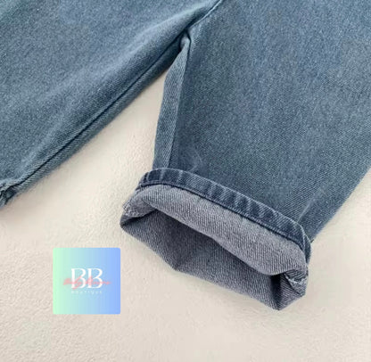 Close-up of blue jeans on a white background with a brand logo in the corner.