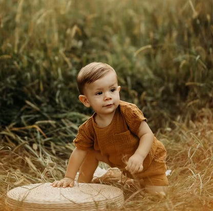 Child in a brown outfit standing in a field with a woven basket