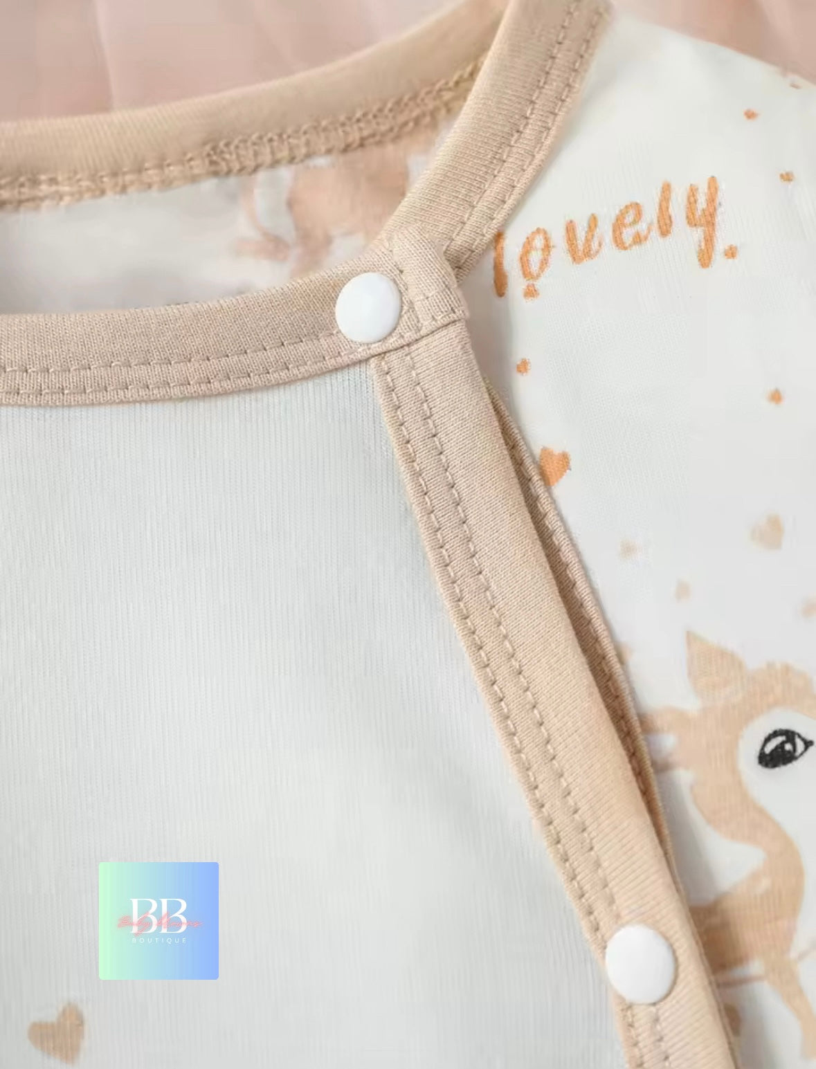 Close-up of a baby outfit with a deer design and 'lovely' text on a white background.