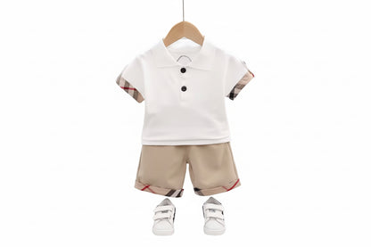 Children's outfit with white polo shirt and beige shorts on a hanger against a light gray background.