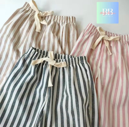 Three pairs of striped pants in beige, black and white, and pink and white with a brand logo in the corner.
