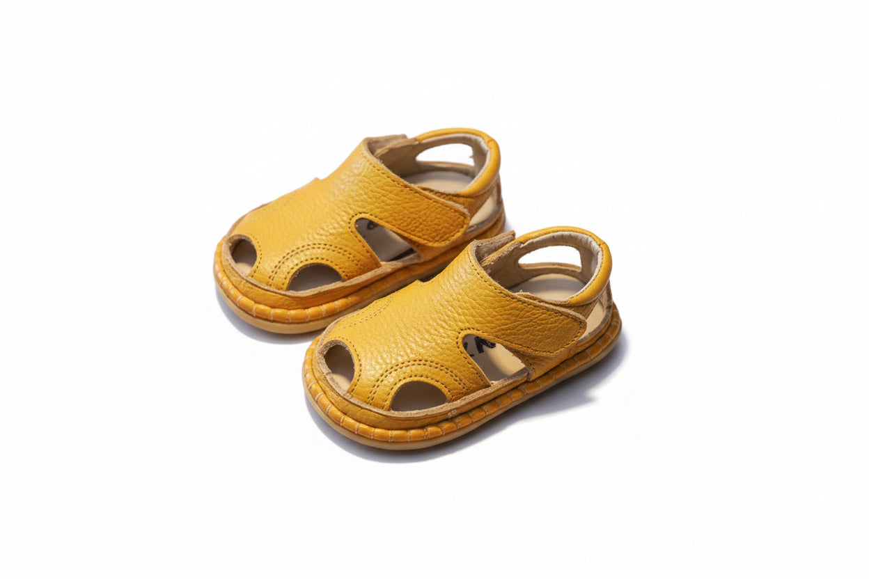 Pair of yellow children's sandals on a brown surface