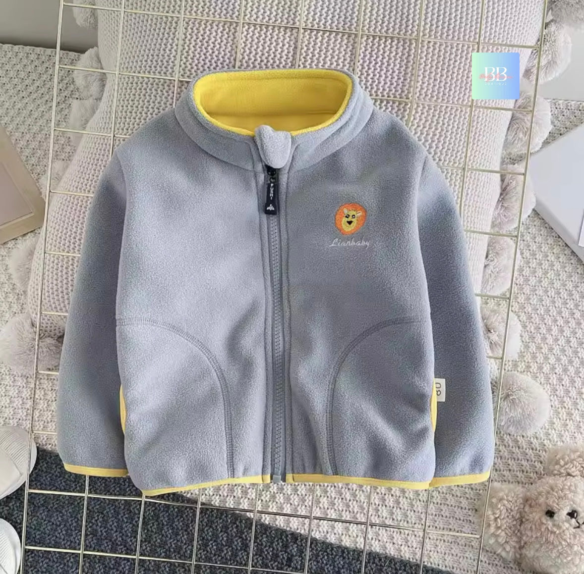 Gray children's jacket with yellow trim on a tiled floor