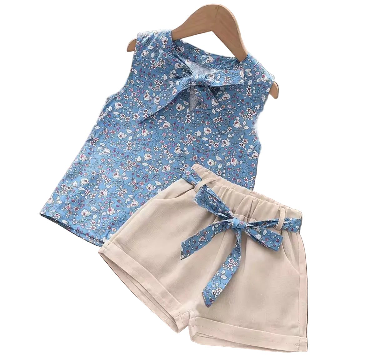 Children's outfit with blue floral top and beige shorts on a wooden surface.