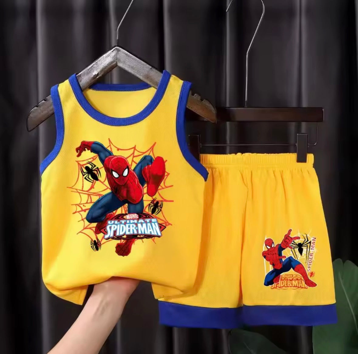 Yellow tank top and shorts set with Spider-Man design on a hanger against a dark background.