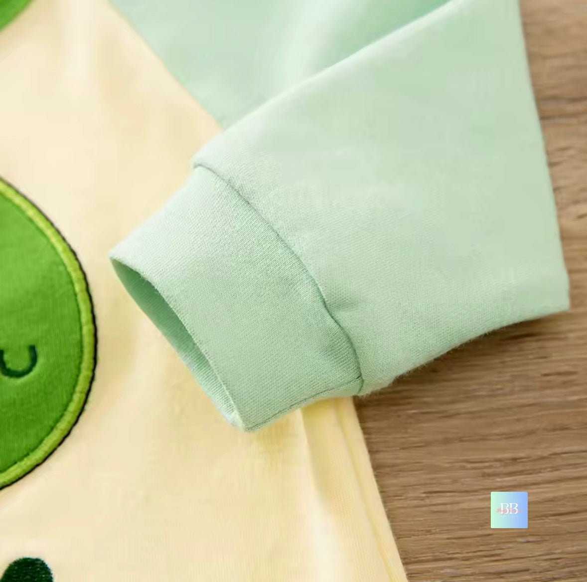 Close-up of a green sleeve on a garment with a wooden surface in the background