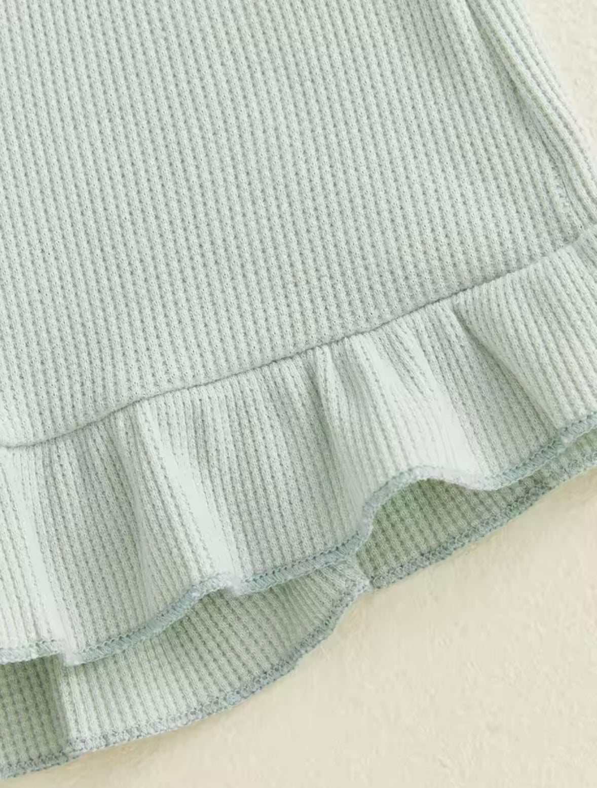 Light blue textured fabric with a ruffled edge on a beige background