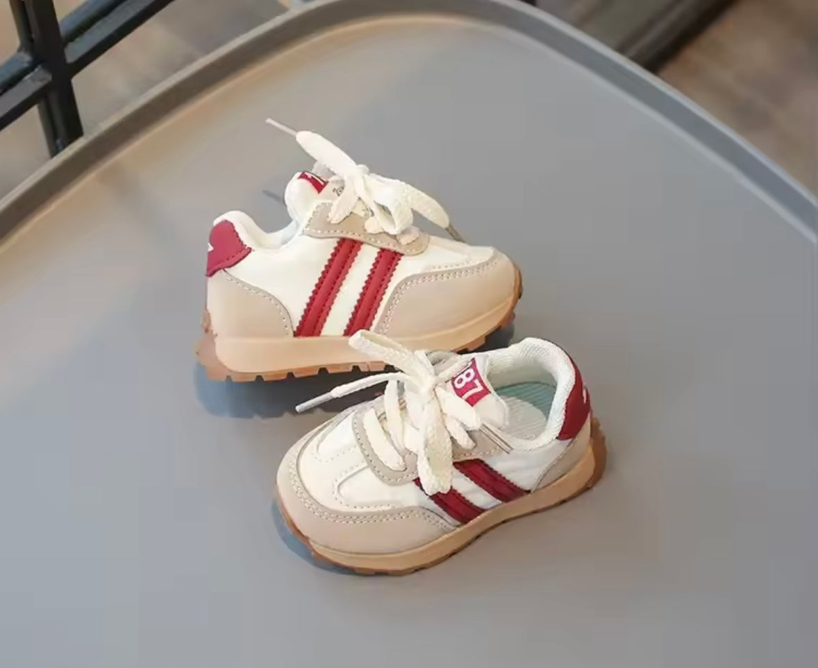 Pair of white and red sneakers on a gray surface