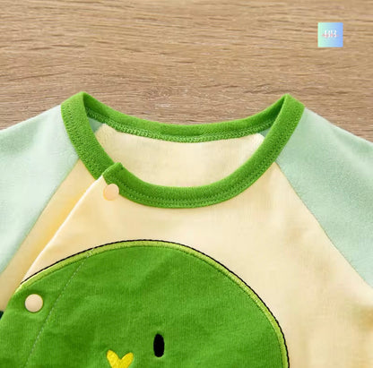 Children's outfit with green and beige design on a wooden surface