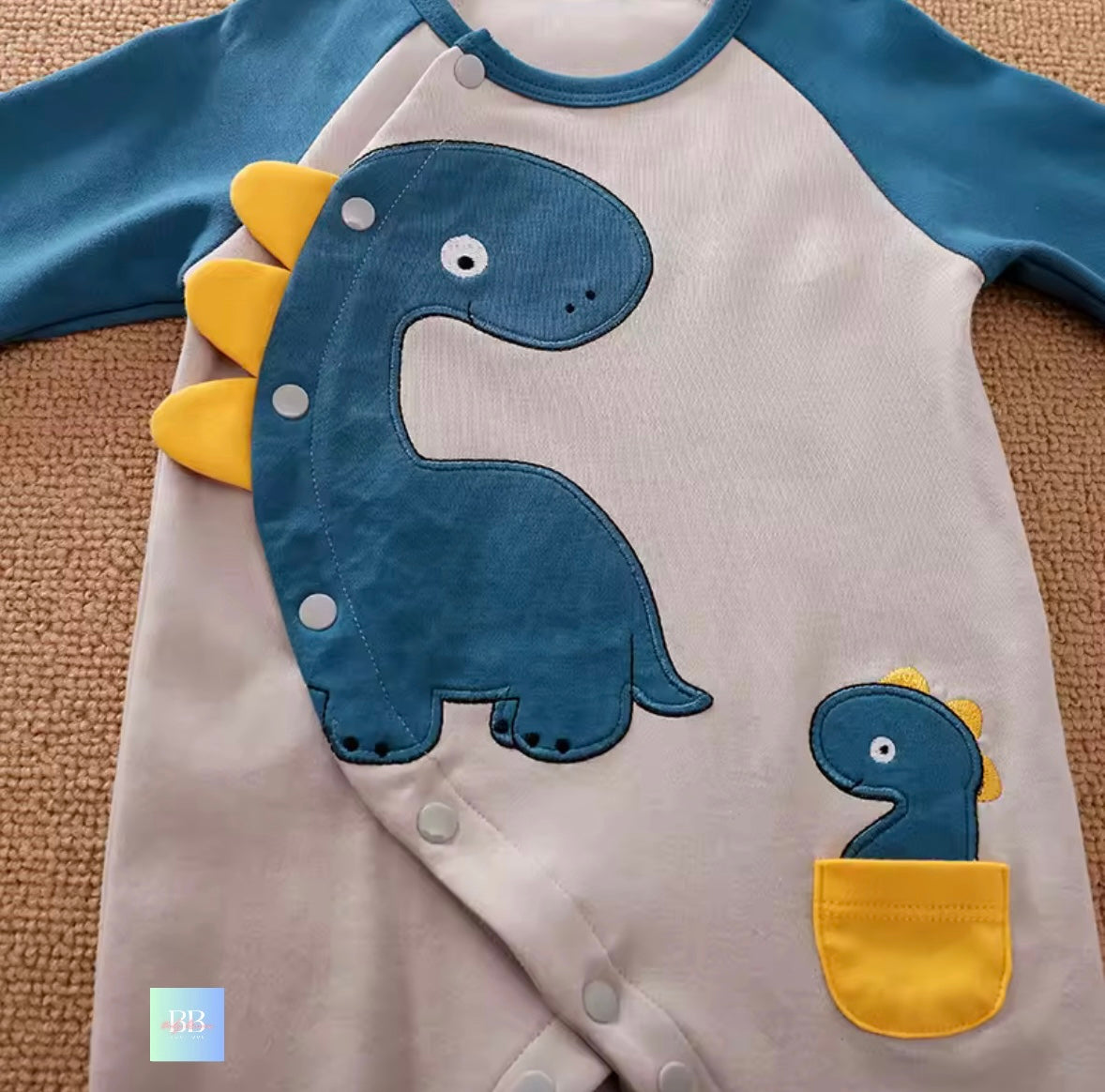 Children's onesie with dinosaur design on a textured surface