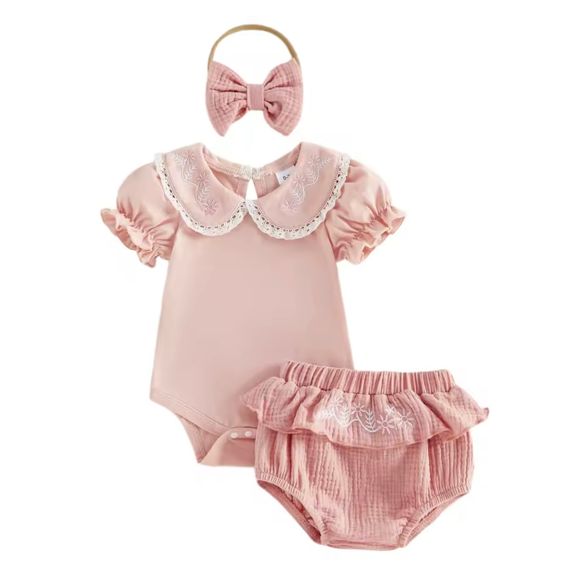 Pink baby outfit with ruffled collar, bloomers, and headband on a white background
