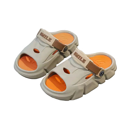 Beige sandals with orange soles on a gray surface, next to a white box labeled 'Clothing'.