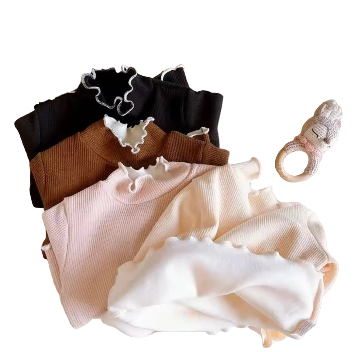 Set of ruffled tops in black, brown, and beige on a textured surface with teddy bears in the background.