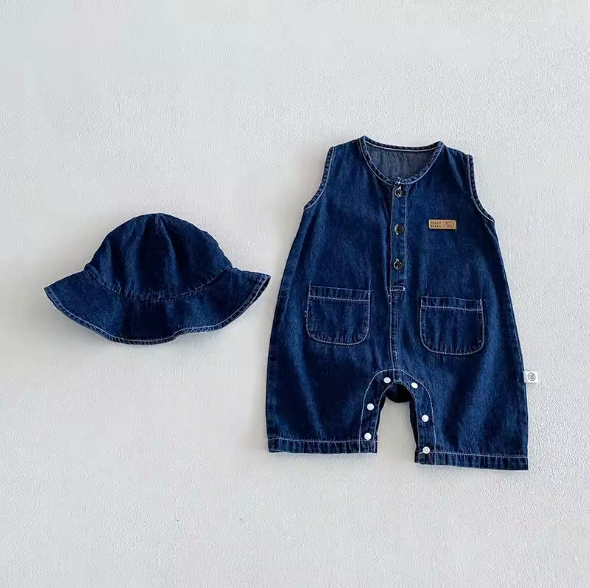Denim baby romper and hat set on a light gray background