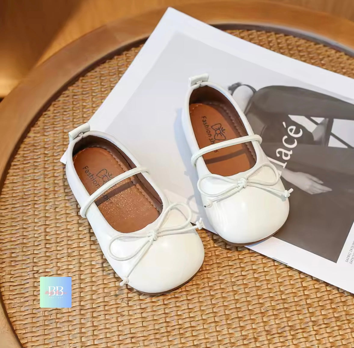 White children's shoes with bows on a woven surface