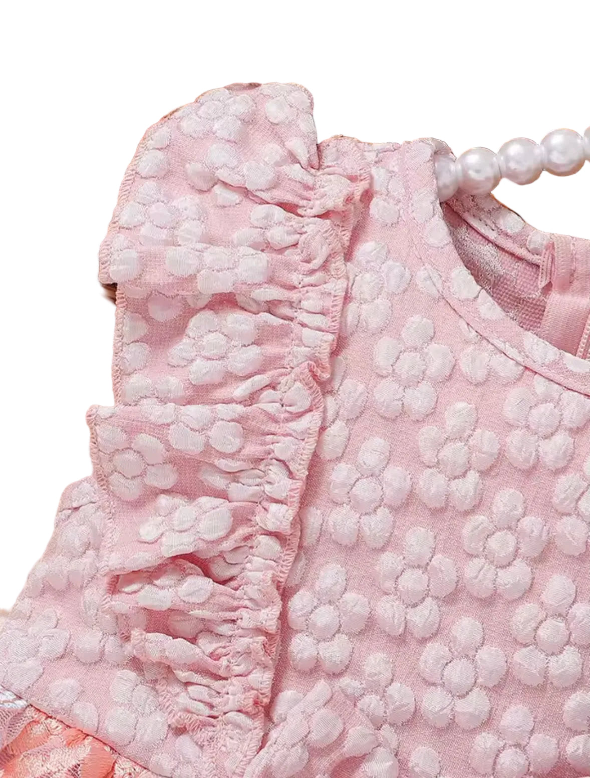 Close-up of a pink textured garment with ruffled details, placed on a woven surface.