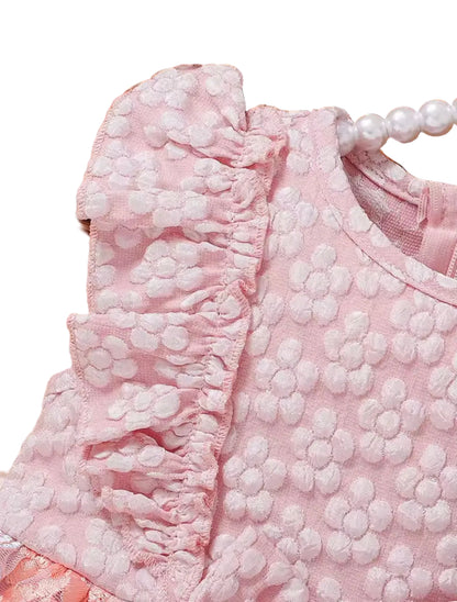 Close-up of a pink textured garment with ruffled details, placed on a woven surface.