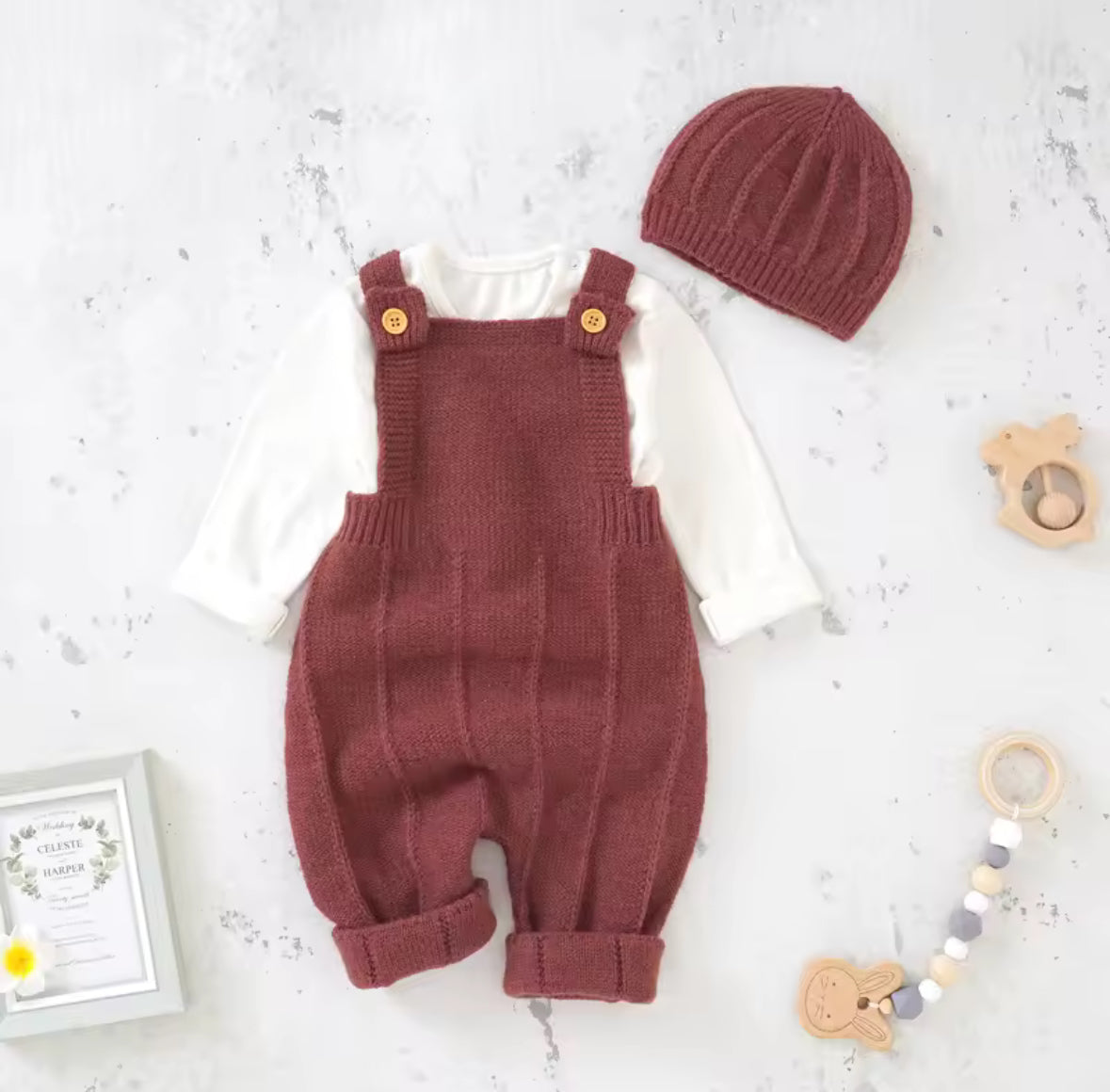 Knitted baby romper with overalls and matching hat on a light background