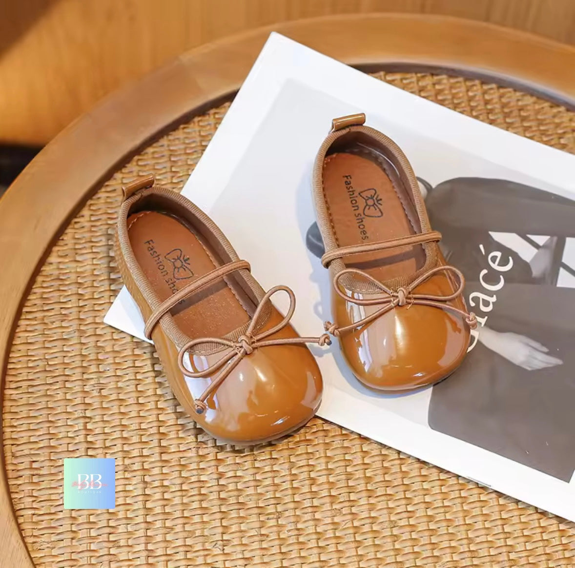 Pair of brown children's shoes with a bow on a woven surface