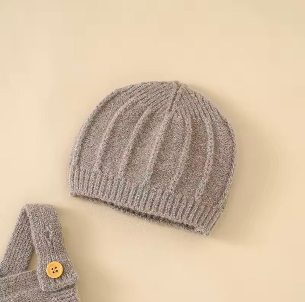 Knitted gray baby hat with a matching scarf on a beige background