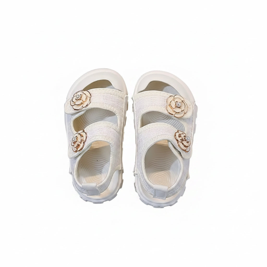 White sandals with floral embellishments on a gray surface