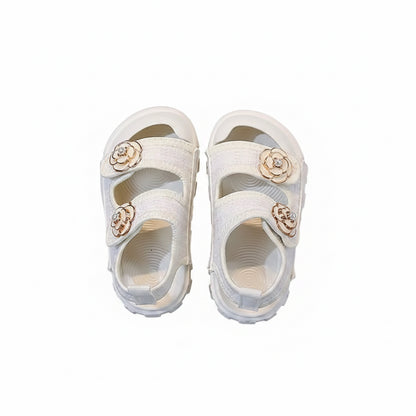 White sandals with floral embellishments on a gray surface
