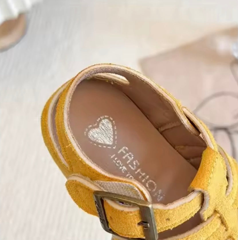 Yellow sandal with a visible brand logo on a light background