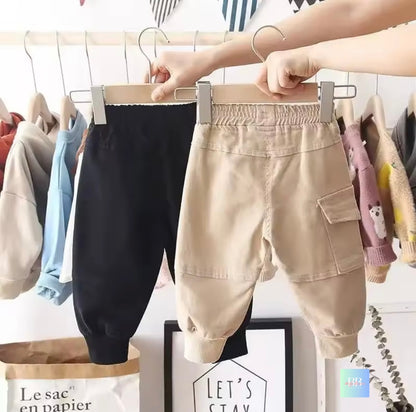 Two pairs of children's pants on hangers with a blurred background.
