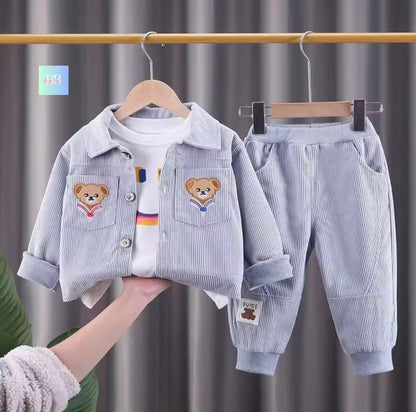 Children's outfit with jacket, shirt, and pants on hangers against a gray curtain background.