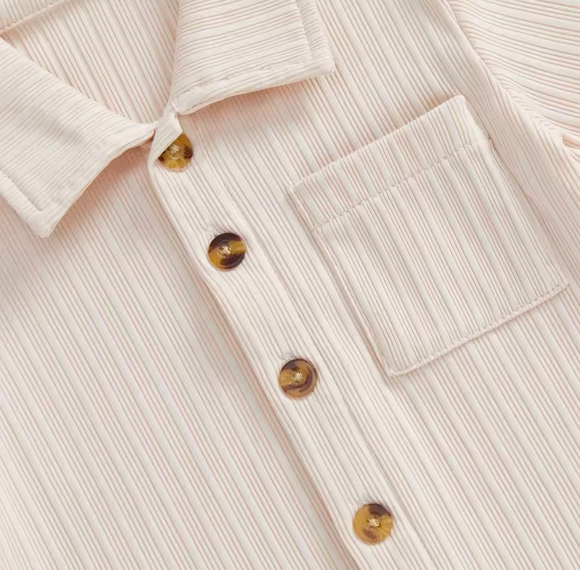 Close-up of a beige ribbed sweater with button details