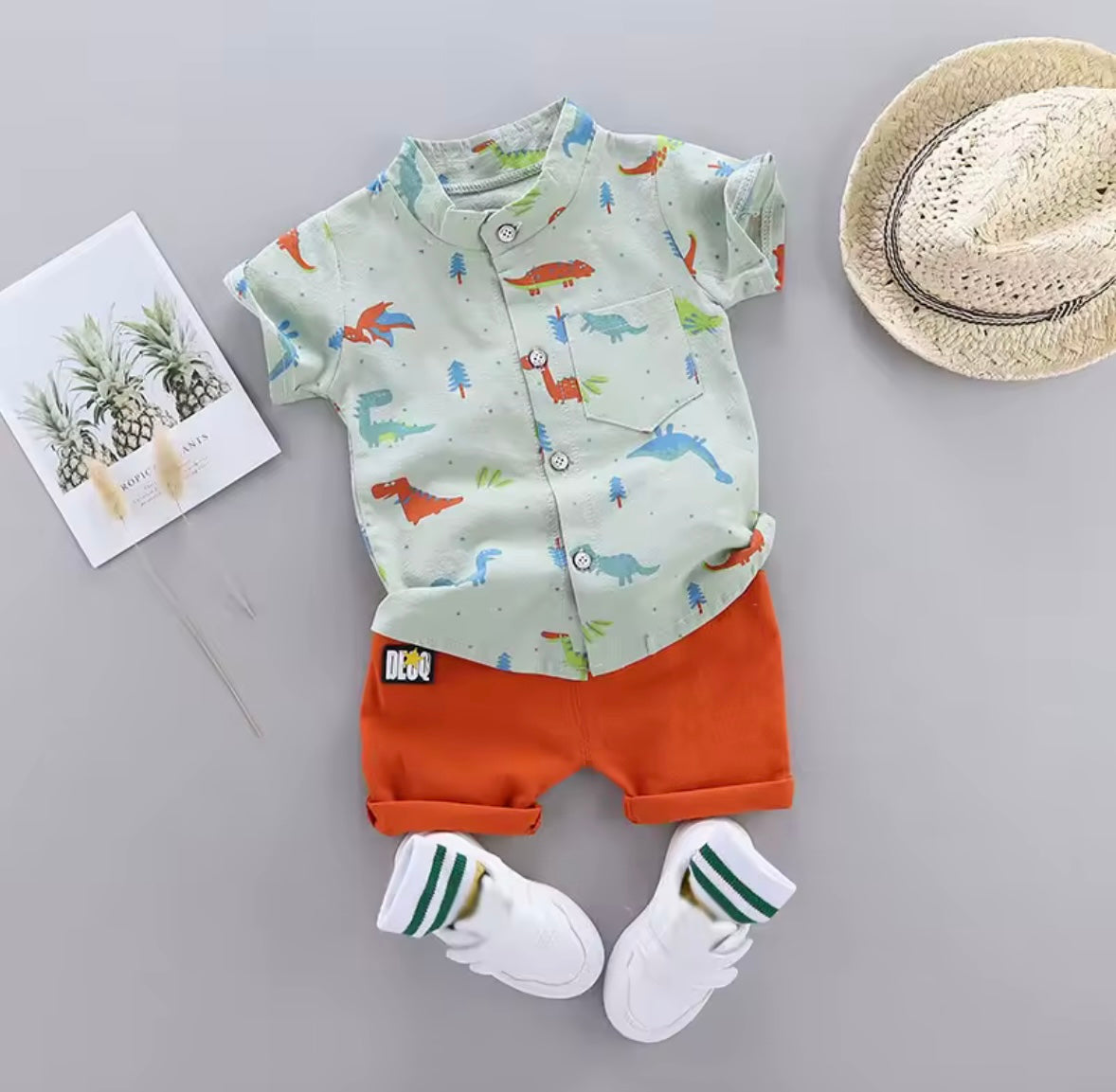 Children's outfit with shirt, shorts, socks, and hat on a gray background