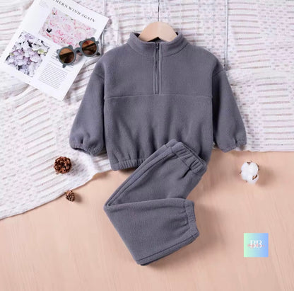 Gray fleece set with pants on a textured surface with a magazine and sunglasses.