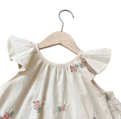White dress with floral embroidery on a hanger against a neutral background