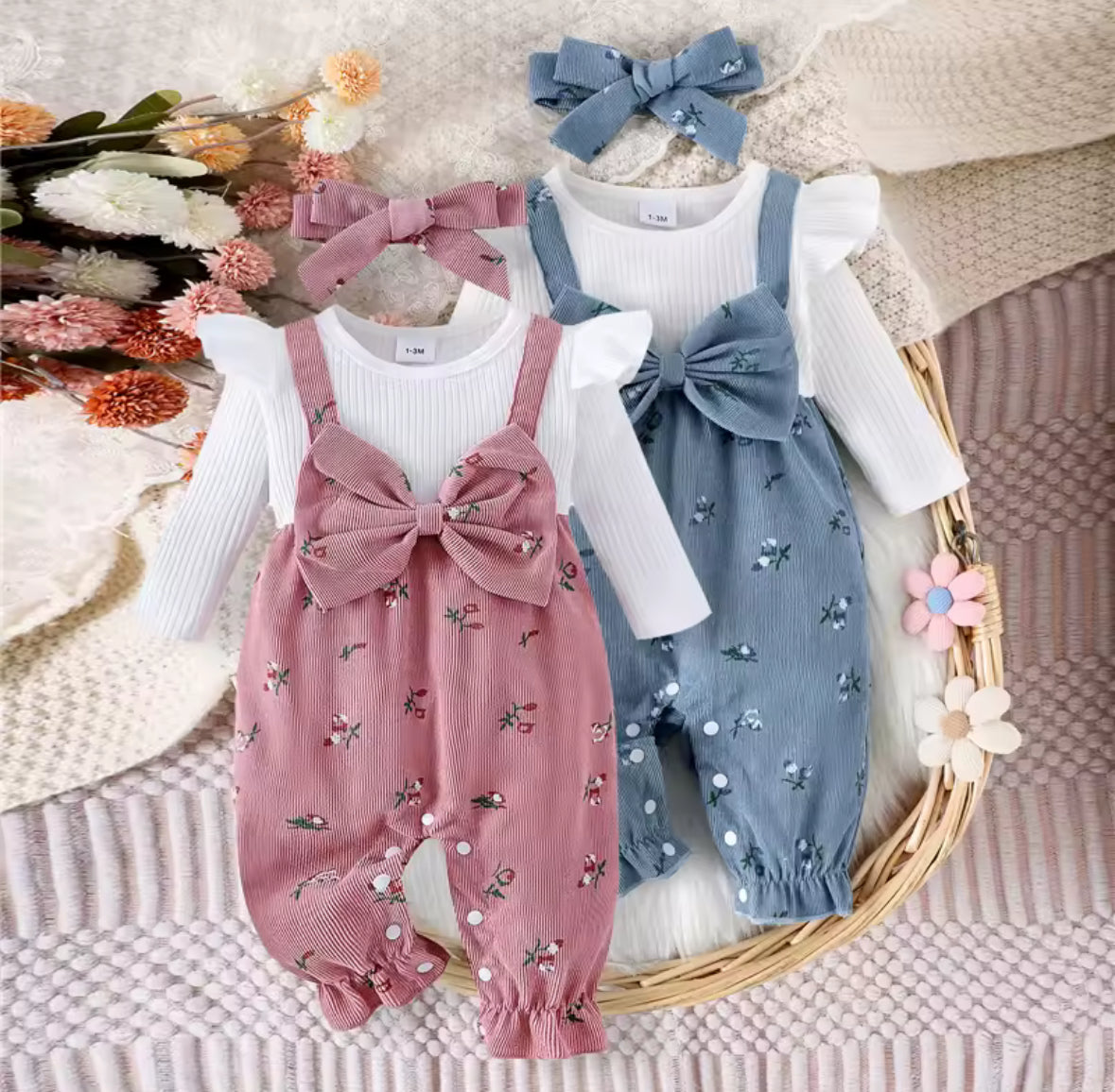 Two baby rompers with floral patterns and matching headbands on a textured surface with flowers.