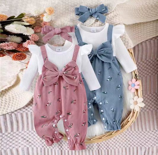 Two baby rompers with floral patterns and matching headbands on a textured surface with flowers.